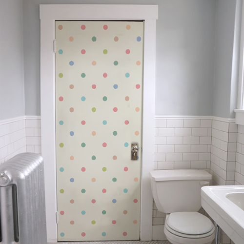 Salle de WC avec un sticker adhésif à pois multicolores sur la porte pour la salle de bain blanche