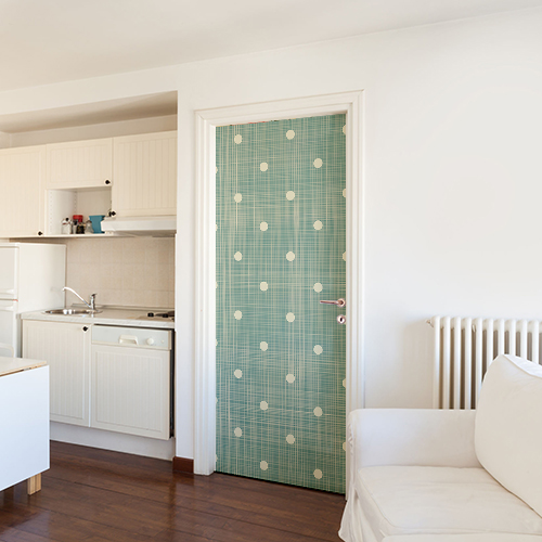 Salle de séjour blanche avec un sticker vert à pois blancs sur la porte