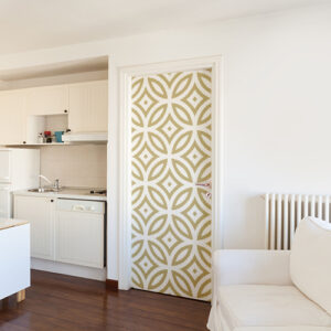 Grand studio aux murs blancs décoré avec un sticker frise géométrique dorée et blanche collée sur la porte.