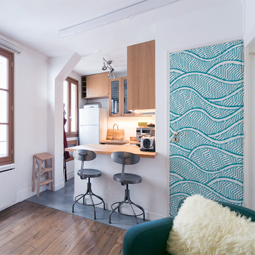 Petit appartement bien rangé avec un sticker bleu représentant des vagues collé sur la porte