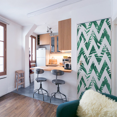 Studio avec cuisine indus et porte personnalisée avec décor adhésif pour porte Jungle chevrons blanc et vert. Cet adhésif collable s'intègre dans un décor moderne usine cosy